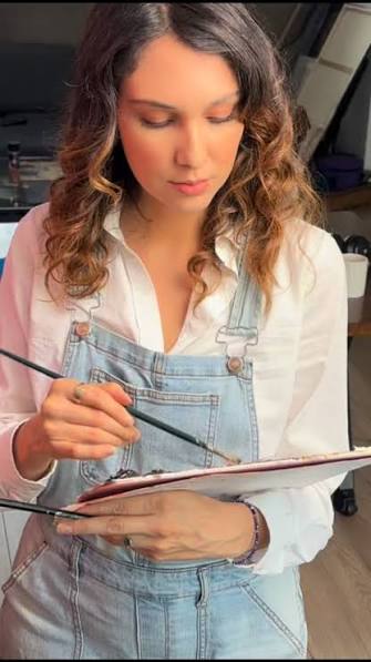 Celeste Lomelí con paleta y pincel trabajando en una pintura