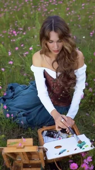 Celeste Lomelí pintando al aire libre entre flores cosmos